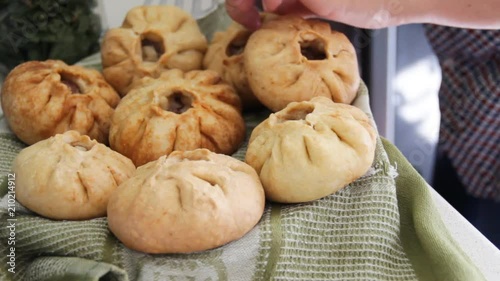 Prepared vak belyash - bashkir national homemade meat pies at home kitchen. Housewife put fresh hot pastry on the cloth photo