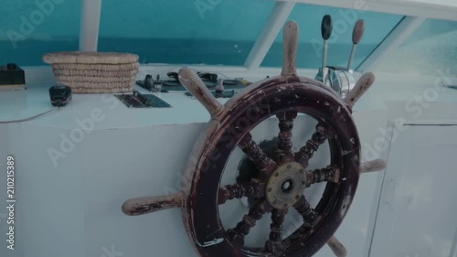 Retro steering wheel, steering wheel and navigation compass on a yacht against the background of a deserted desert island. The concept of business or life management, vacation or tourism. dolly shot