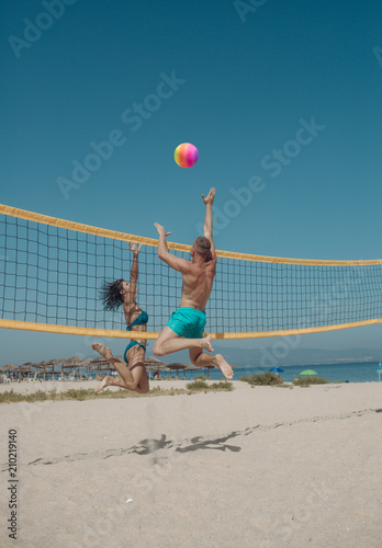 Couple have fun playing volleyball. Young sporty active couple beat off volley ball, play game on summer day. Woman and man fit, strong, healthy, doing sport on beach. Beach volleyball concept