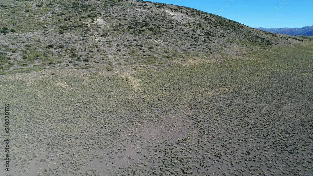 Aerial drone scene of estepa hill in epu lauquen, north of neuquen, Patagonia Argentina. Camera moving forwadrs and up, discovering big mountains at Andes mountains with snow.