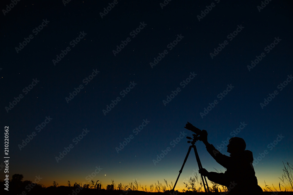 The astronomer photographs the night starry sky on a digital camera using a tripod.