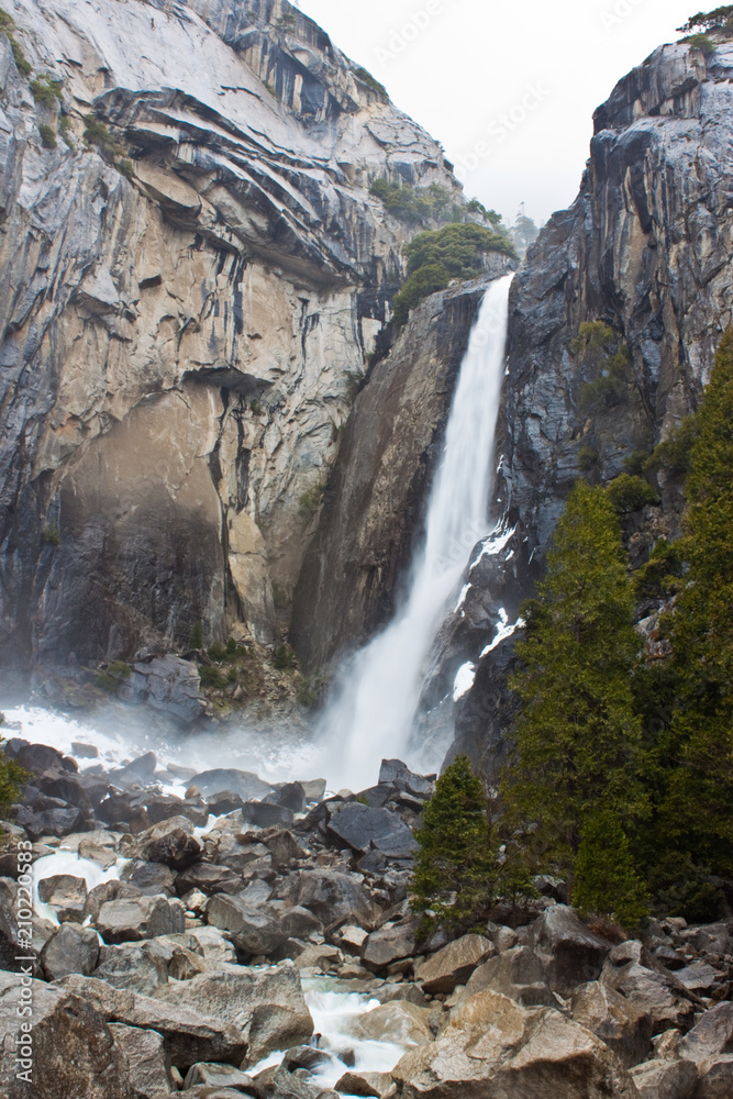 Obraz premium Waterfall in Yosemite, with trees and rocks
