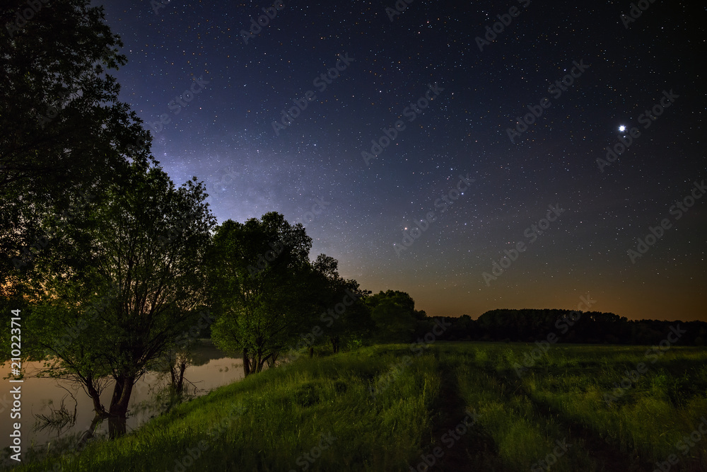 The rural road is photographed at dusk on the evening sunset flank. The sky with the clouds is lit by the sun. Long exposure. The rural road is photographed at dusk on the evening sunset flank. The sky with the clouds is lit by the sun. Long exposure.