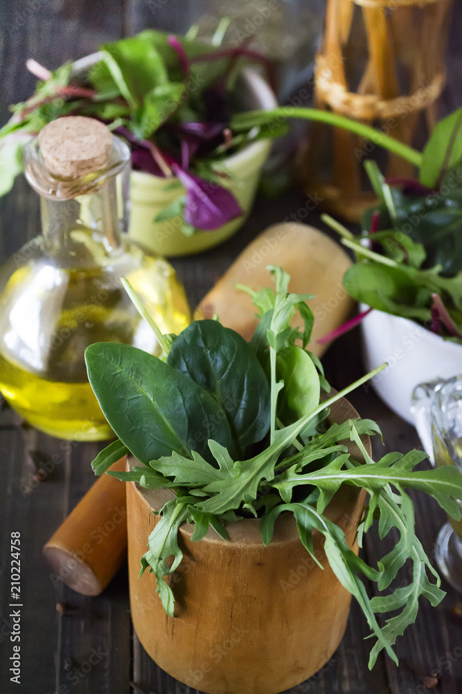 arugula leaves and spinach in a wooden mortar on a dark wooden background arugula leaves and spinach in a wooden mortar on a dark wooden background