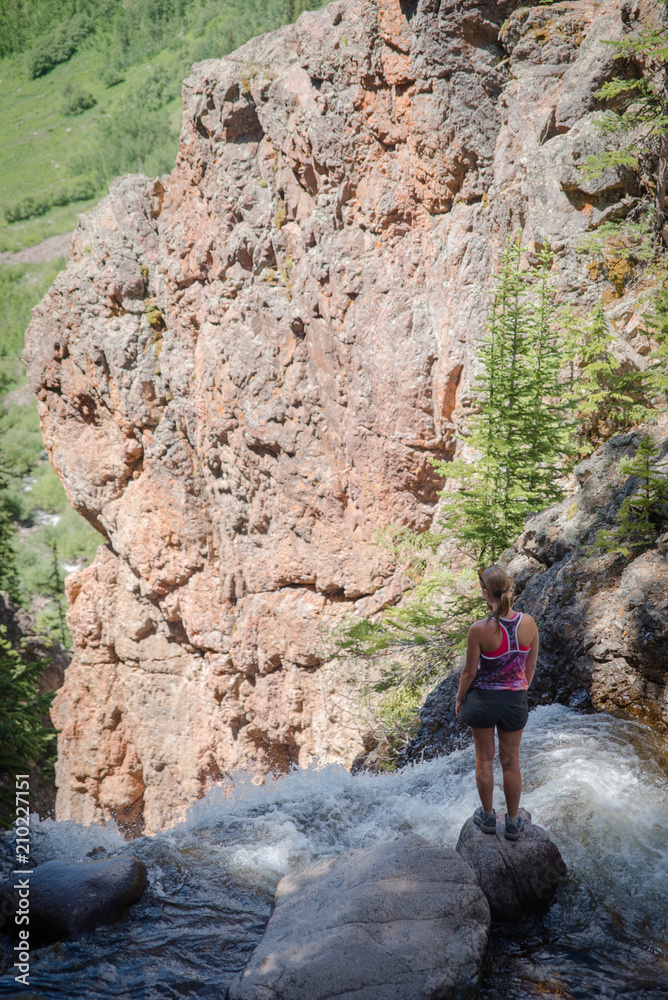 A woman standing near the edge of Booth Falls in Vail, Colorado. 