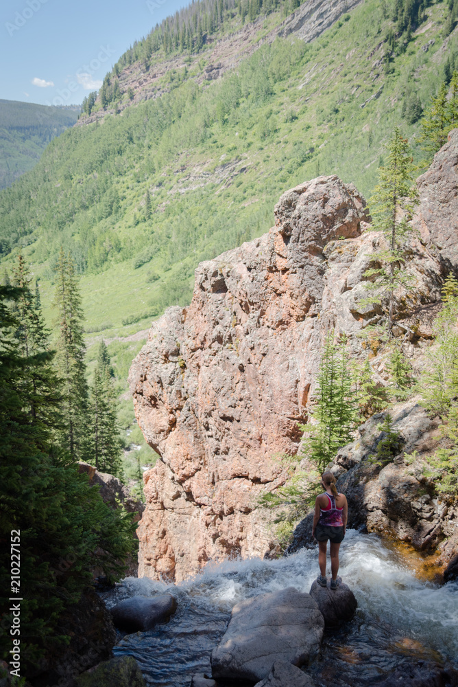 A woman standing near the edge of Booth Falls in Vail, Colorado. 