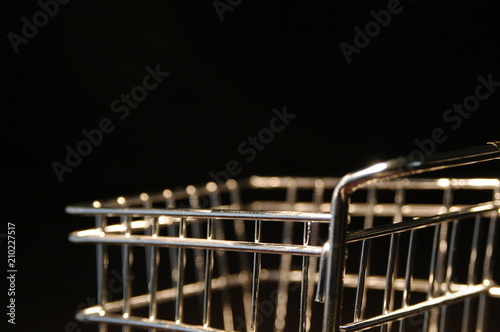 Close up of a small shopping cart on a black background. Silver metal shopping cart shot with macro lens shallow depth of field. Shopping and commerce concept.