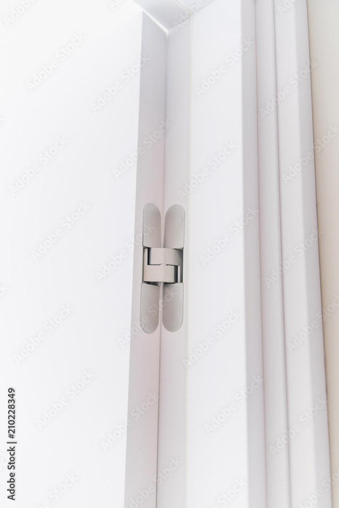 New modern metal door hinges on white wooden doors. Hidden chrome door hinges on stylish door. New modern metal door hinges on white wooden doors. Hidden chrome door hinges on stylish door.