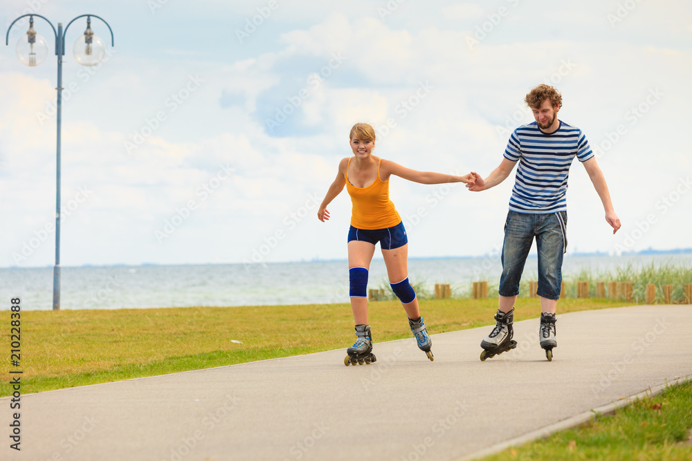 Obraz premium Young couple on roller skates riding outdoors