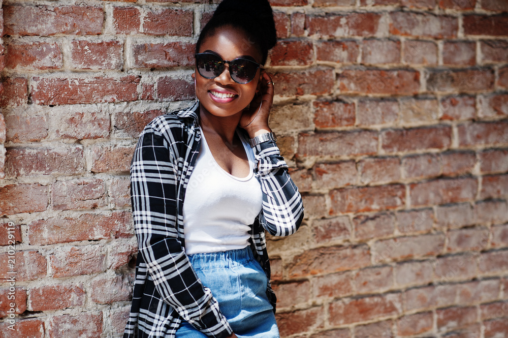 Hip hop african american girl on sunglasses and jeans shorts. Casual street fashion portrait of black woman.
