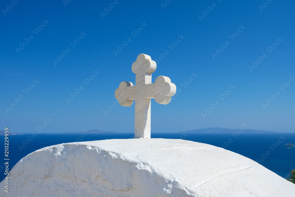 Cycladic greek orthodox church on Paros island, Greece. White cross against blue sea and sky Cycladic greek orthodox church on Paros island, Greece. White cross against blue sea and sky