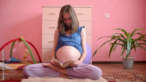 Pregnant Woman Reading A Book sitting on the floor of Bedroom