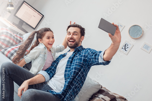 Father and little daughter at home sitting taking seflie photos smiling cheerful photo