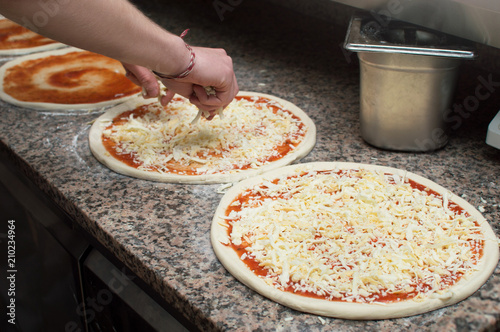 Cook in the kitchen putting the ingredients on the pizza. Pizza concept. Production and delivery of food.