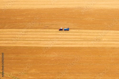 Aerial view of a tractor harvesting a yellow field.