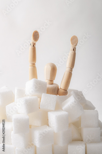Obraz na płótnie Sugar addiction, insulin resistance, unhealthy diet and November 14 is diabetes awareness day concept with a puppet drowning in sugar cubes isolated on white background and copy space for text w salonie