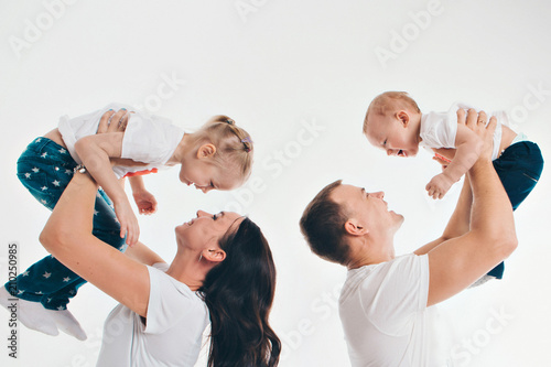 family portrait on the floor on white background. parents hold children in their arms.A man and a woman lifted a boy and a girl up