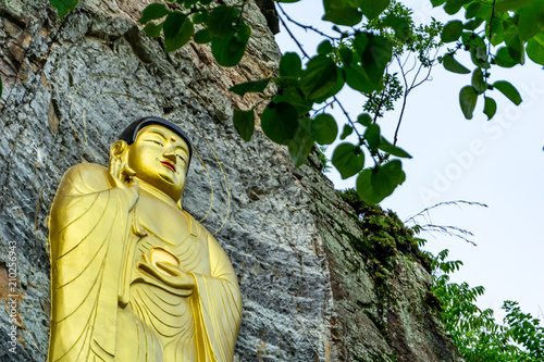 Golden Buddha image statue craft on the rock cliff