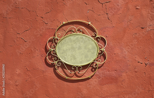 Mexican decorative oval frame, welding work on red old wall.