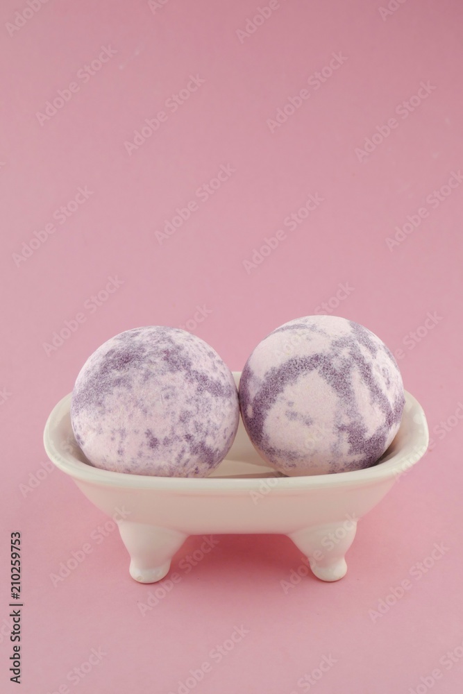 Lavender bath bombs in a ceramic bath on a light pink background. natural vegan organic body cosmetics Lavender bath bombs in a ceramic bath on a light pink background. natural vegan organic body cosmetics