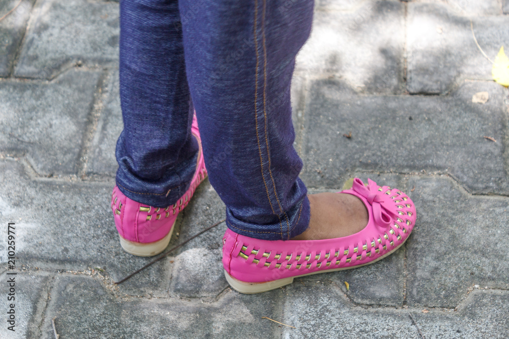 young girl children's seen wearing colorful modern unidentified footwear.standing in different styles and poses for a photograph with selective focus.wearing leggings and standing on their own shadow