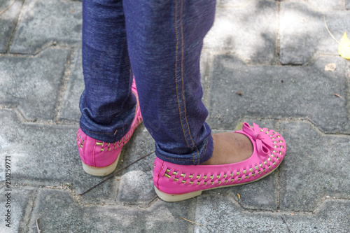 young girl children's seen wearing colorful modern unidentified footwear.standing in different styles and poses for a photograph with selective focus.wearing leggings and standing on their own shadow