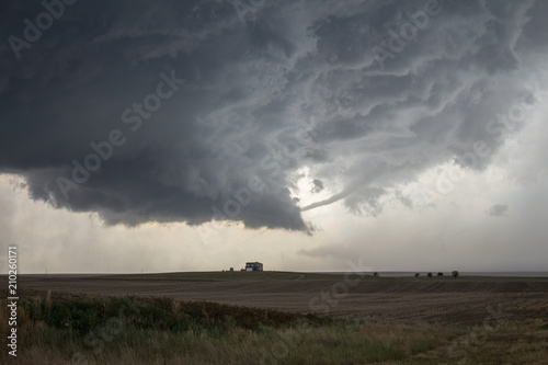 A rope tornado funnel dissipates underneath the updraft of a supercell thunderstorm.
