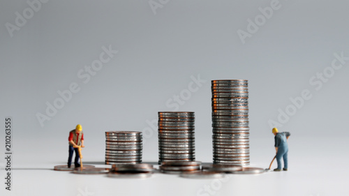 Concept of rising labor costs. A stack of coins and two miniature people.