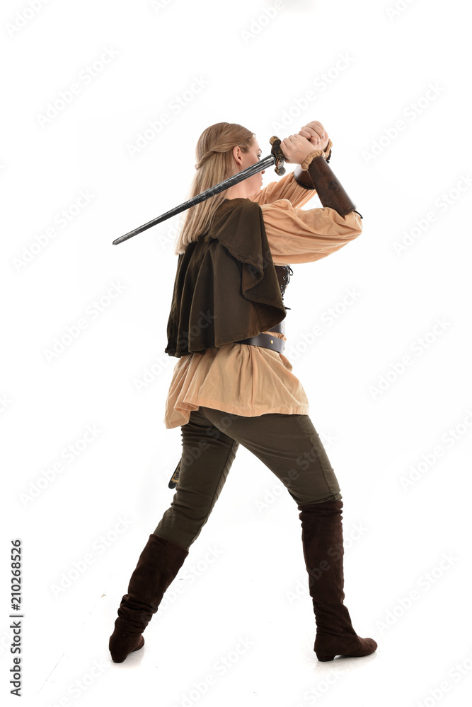 full length portrait of girl wearing medieval costume with sword. standing pose with back to the camera, isolated on white studio background. full length portrait of girl wearing medieval costume with sword. standing pose with back to the camera, isolated on white studio background.