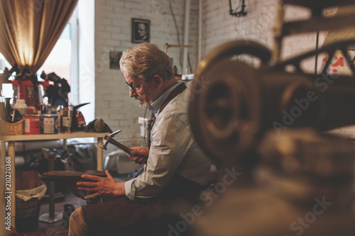 An elderly shoemaker at work