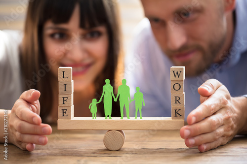 Couple Protecting Balance Between Work And Life On Seesaw photo