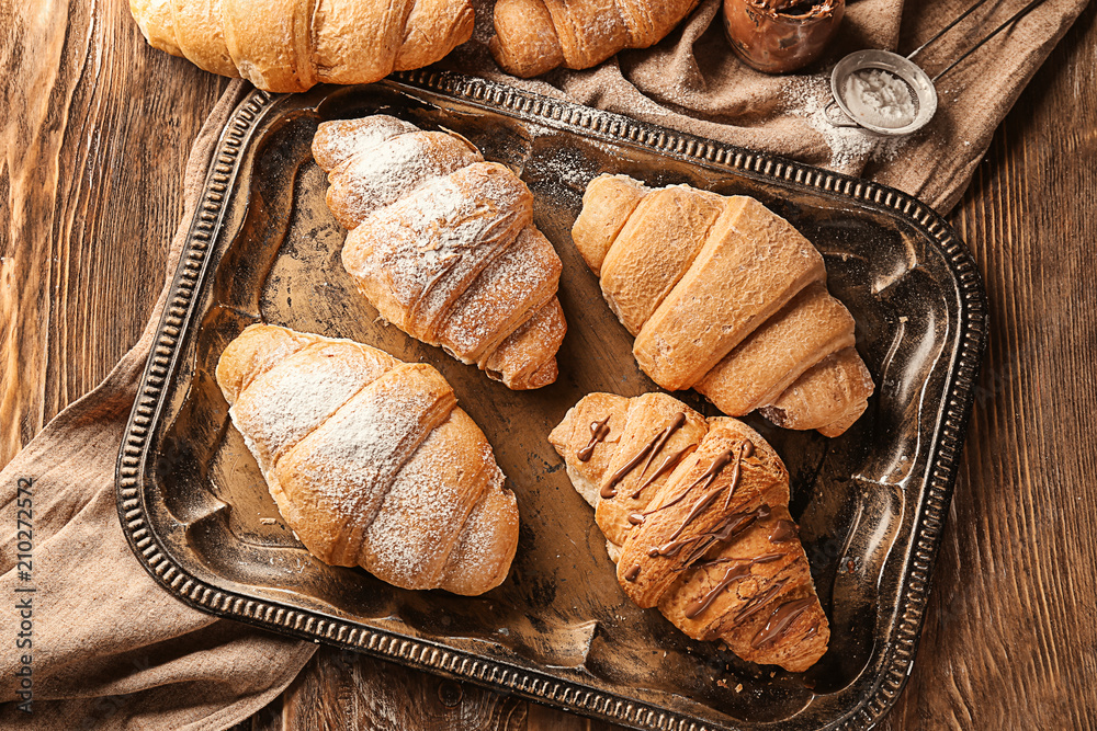 Tray with tasty croissants on wooden background