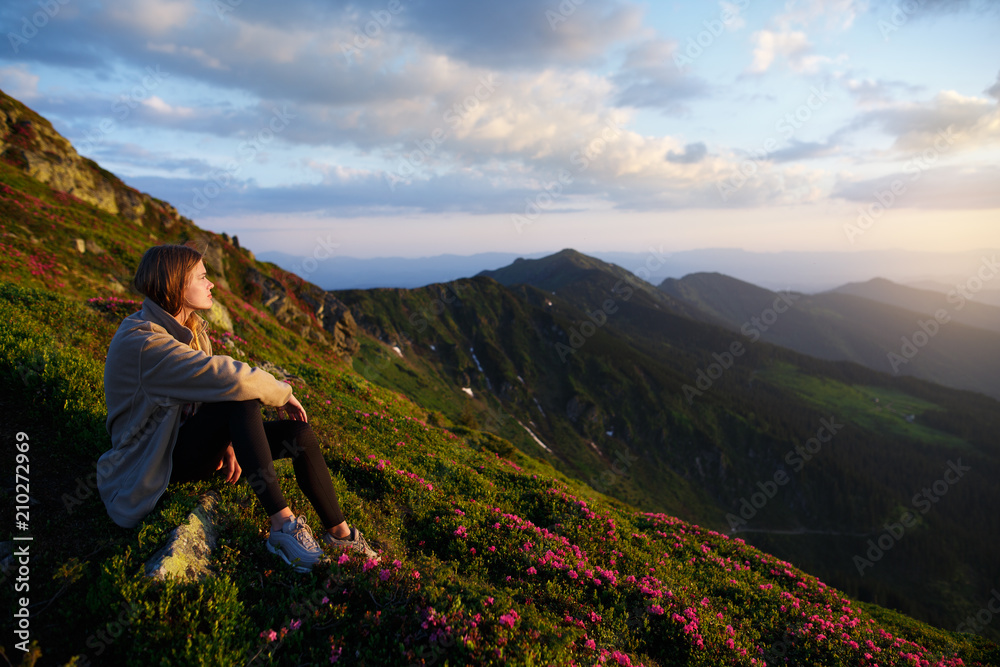 Woman sitting on mountain top and contemplating the sunset