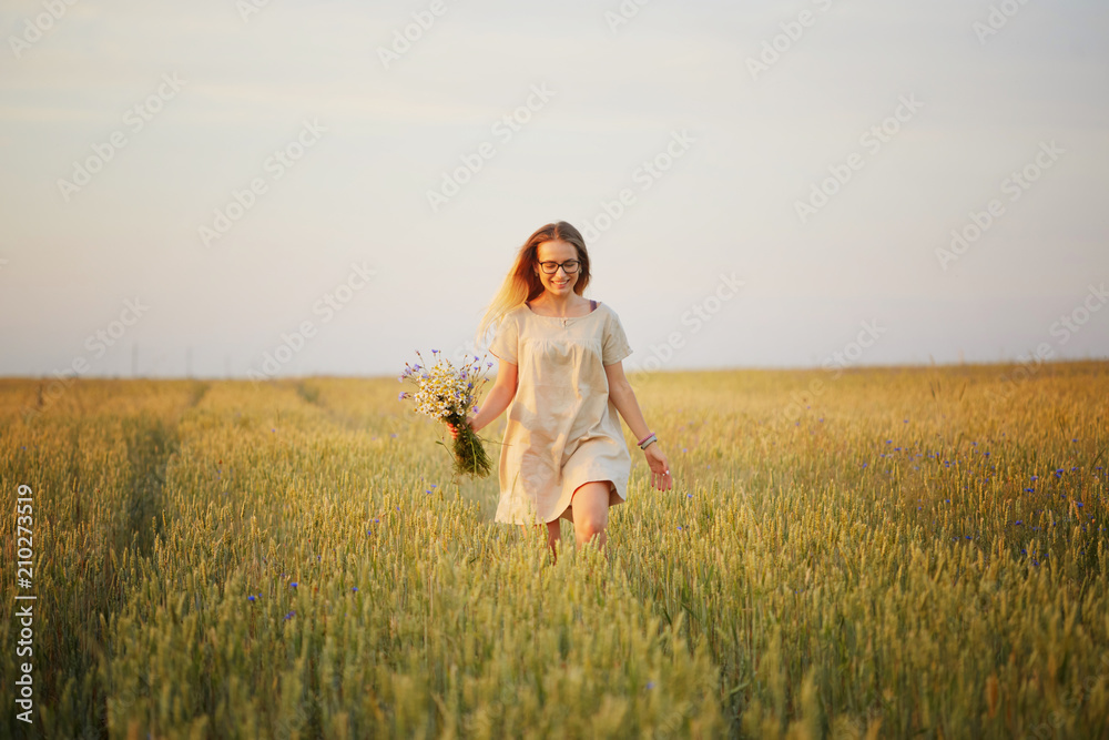 girl with flowers walking on a grain field. girl with flowers walking on a grain field.