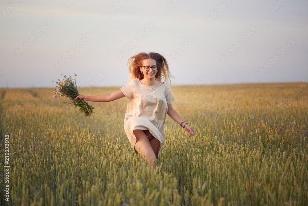 girl with flowers walking on a grain field. girl with flowers walking on a grain field.