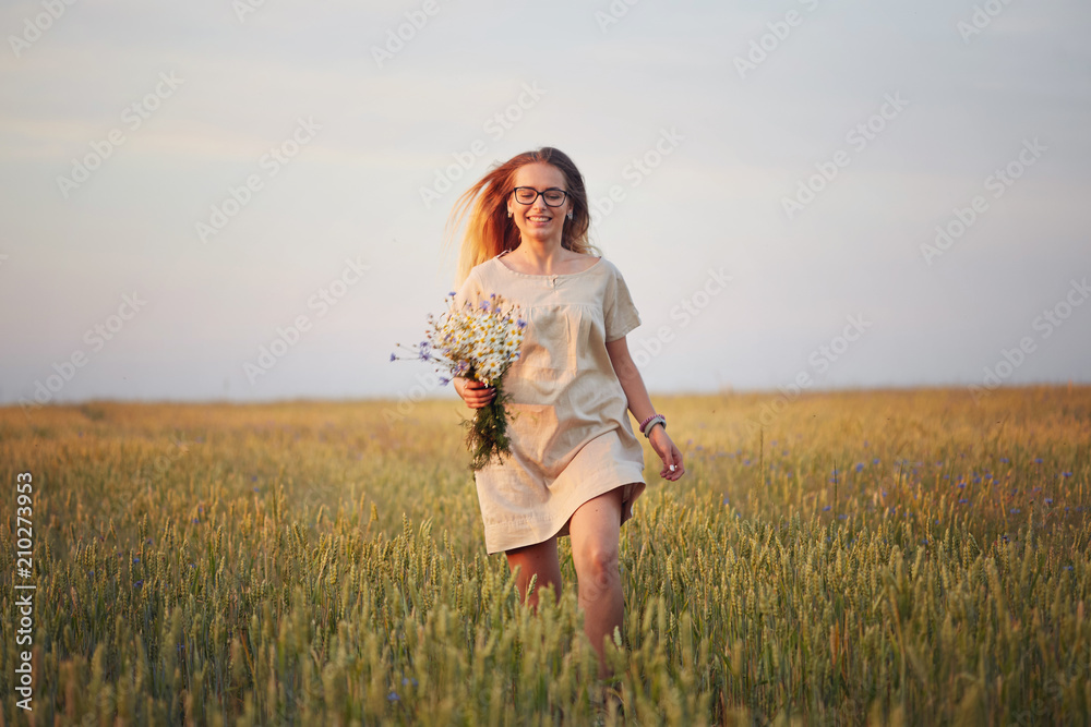 girl with flowers walking on a grain field. girl with flowers walking on a grain field.