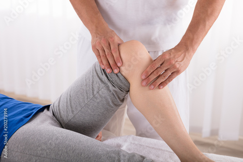 Physiotherapist Giving Knee Exercise To Woman