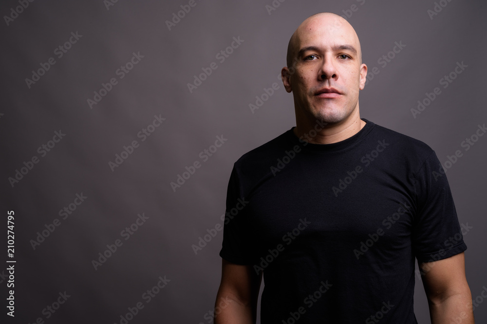 Handsome bald man against gray background