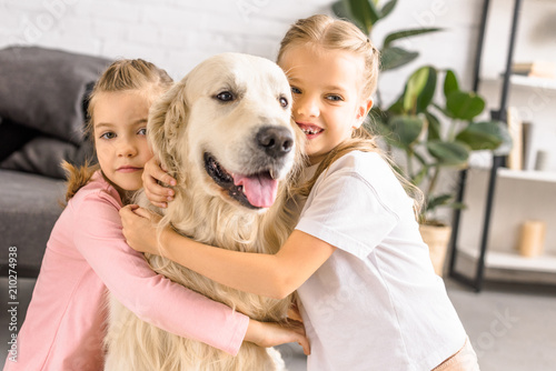 portrait of adorable smiling kids hugging golden retriever dog at home © LIGHTFIELD STUDIOS