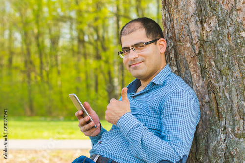 young man sitting under a tree