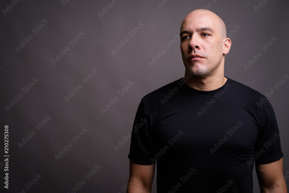 Handsome bald man against gray background