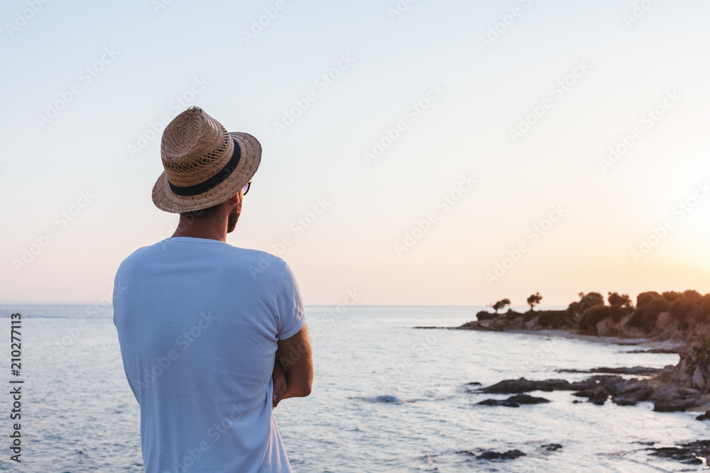 Young man enjoying sunset on a cliff at a seaside