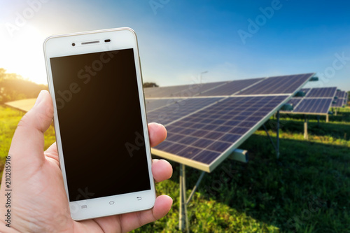 Men use smartphone blurred images in the solar panel background. As Renewable Energy and clean energy.