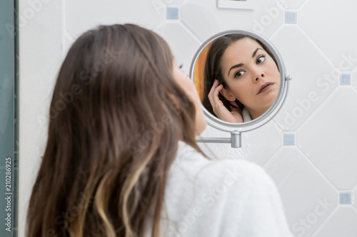 Beautiful woman looking at face in reflection