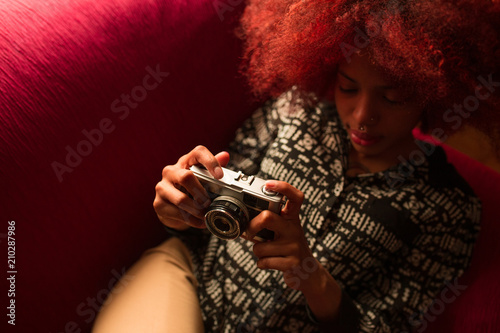 Young ethnic woman with camera on couch