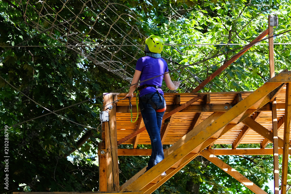 Woman in safety equipment in roping park. Leisure time in rope park. Woman in safety equipment in roping park. Leisure time in rope park.