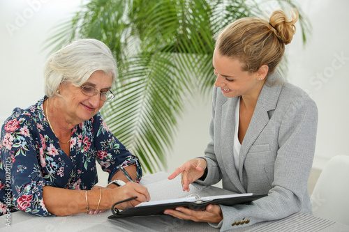 retired woman signing contract with insurance agent