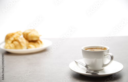 Cup of fresh coffee with croissants on dark background