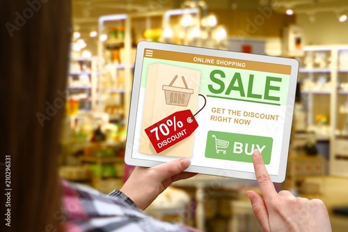 Sale and discount concept, girl holds the digital tablet on blurred shop background