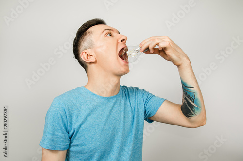 Young guy eating lamp, dressed in a blue t-shirt on a light background.